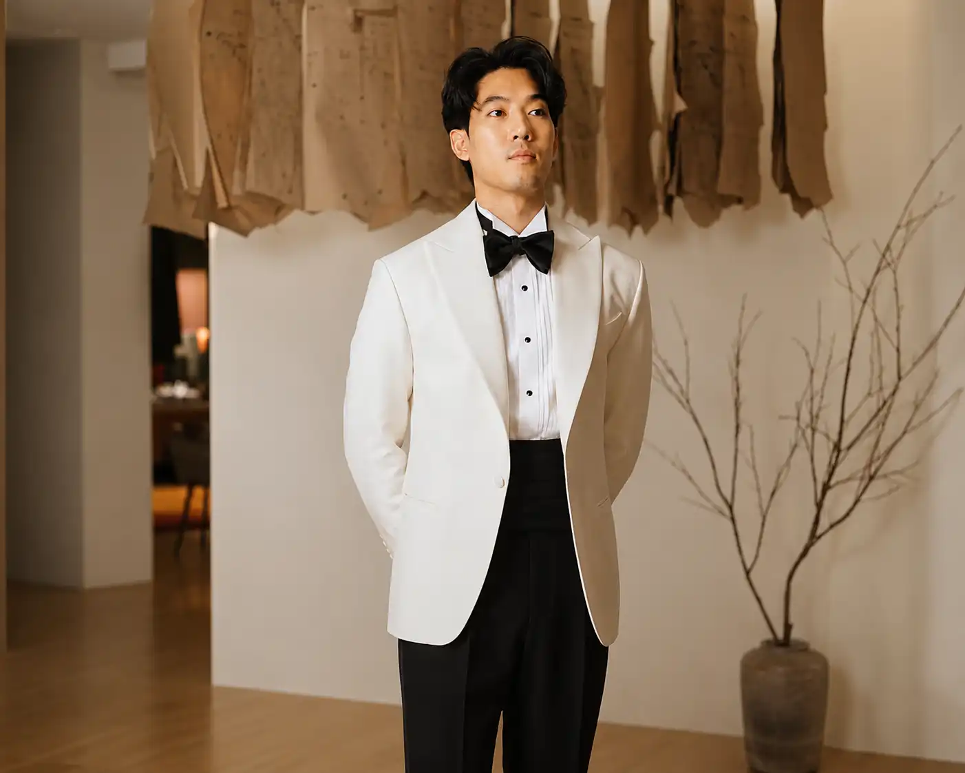 Man wearing a white tuxedo jacket with black trousers and a black bow tie.